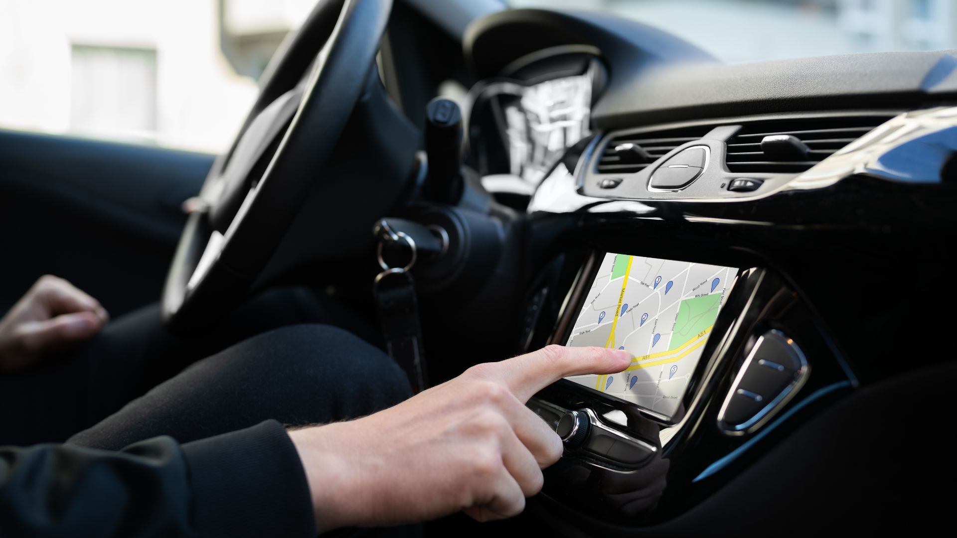 A person is pointing at a map on the dashboard of a car
